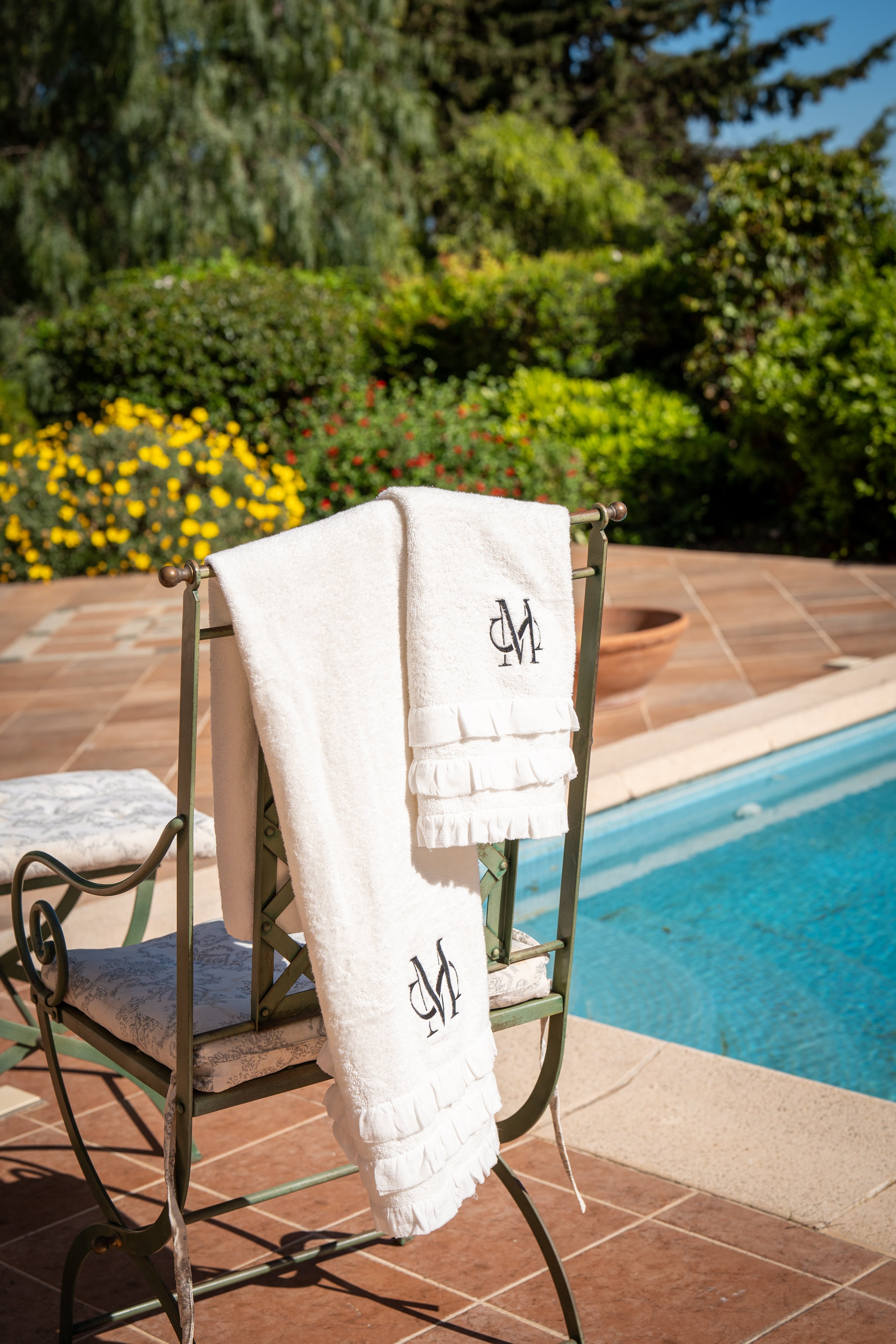 Set de serviettes de bain haut de gamme brodées d'un monogramme, posées près de la piscine